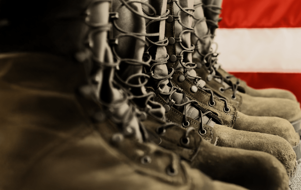Sage green military combat boots with US flag in the background.